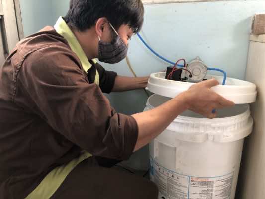 Thanh niên nhà máy kiểm tra dung dịch cồn trước khi phun khử khuẩn tại buồng